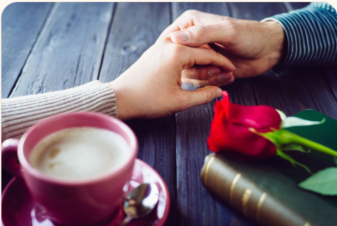 A couple holding hands over coffee